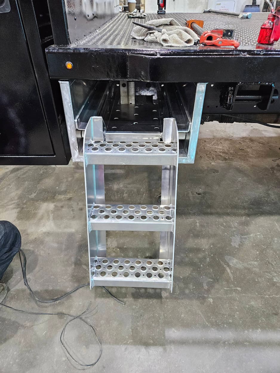 Aluminum truck step ladder attached to flatbed.
